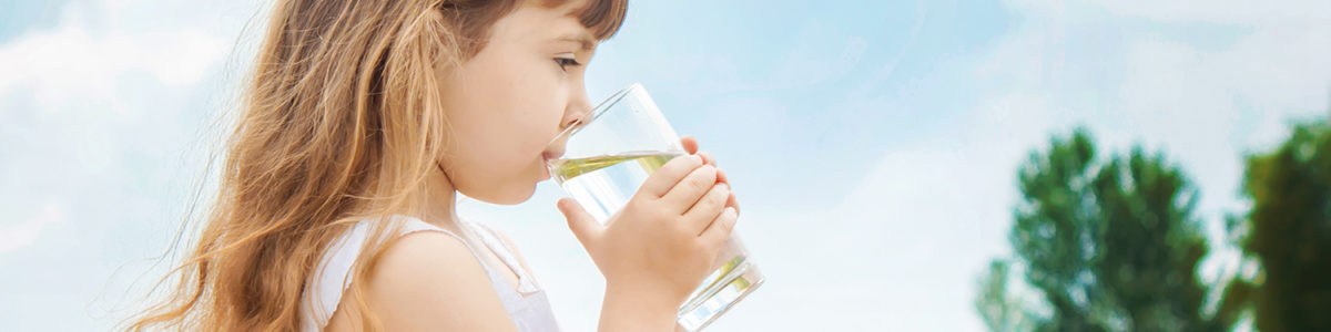 the child holds a glass of water in his hands. selective focus. the child holds a glass of water in his hands. selective focus.
