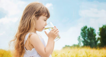 the child holds a glass of water in his hands. selective focus.